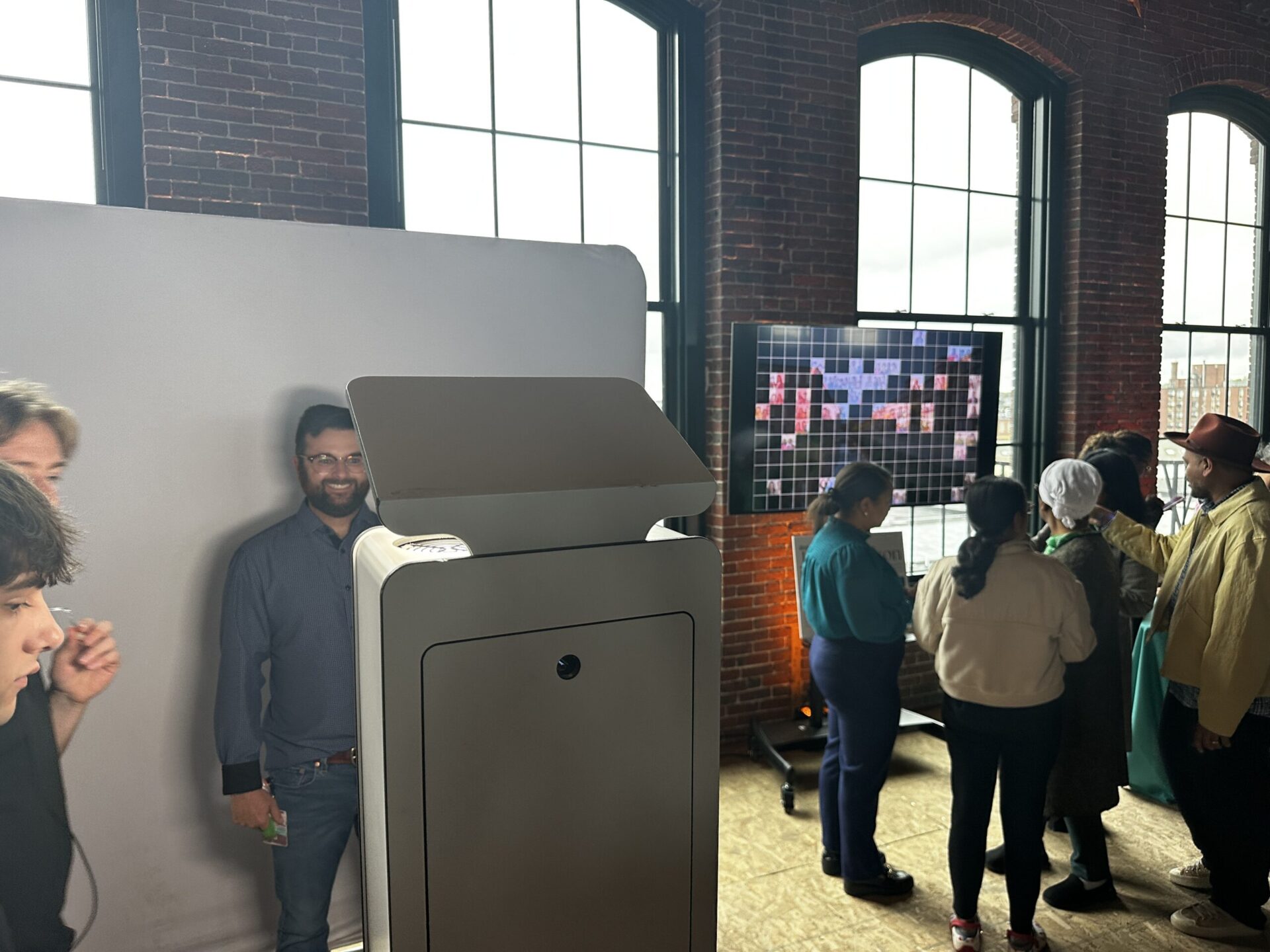 Digital mosaic photo booth setup at a Boston area event, showing the display screen and booth activation area